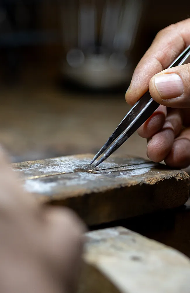 Juwelier bei der präzisen Handarbeit mit einer Pinzette auf einer Werkbank