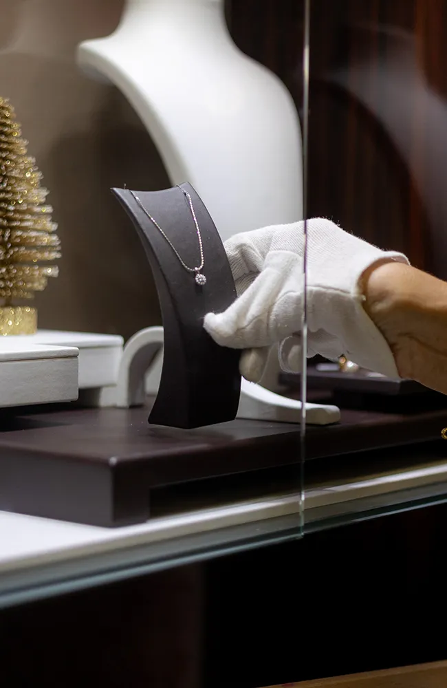 Juwelier präsentiert eine elegante Halskette in einer Schmuckvitrine