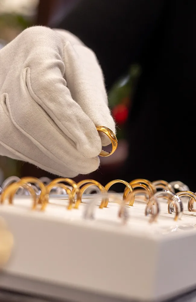 Juwelier präsentiert goldenen Ring mit Handschuh
