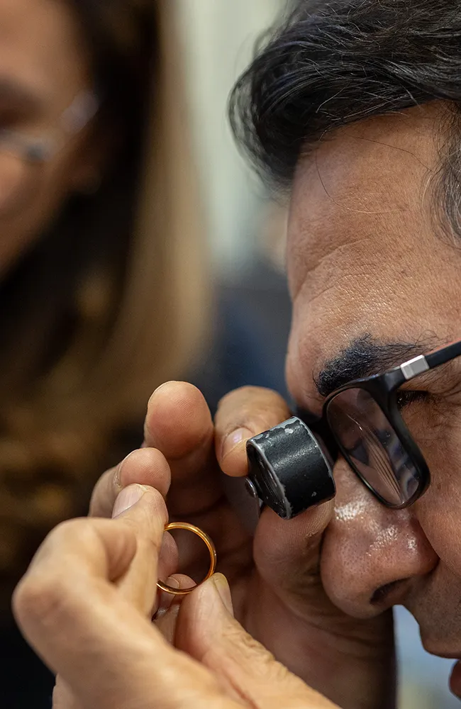 Juwelier prüft einen Goldring mit einer Lupe